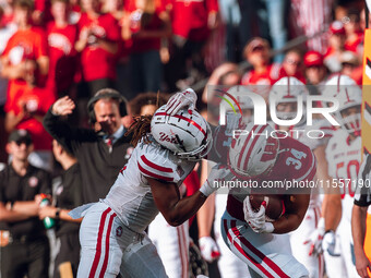 South Dakota defensive back Teven McKelvey #3 grabs the facemask of Wisconsin Badgers running back Jackson Acker #34 at Camp Randall Stadium...