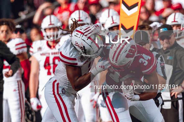 South Dakota defensive back Teven McKelvey #3 grabs the facemask of Wisconsin Badgers running back Jackson Acker #34 at Camp Randall Stadium...