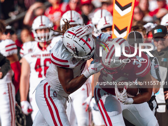 South Dakota defensive back Teven McKelvey #3 grabs the facemask of Wisconsin Badgers running back Jackson Acker #34 at Camp Randall Stadium...