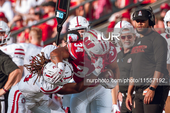 South Dakota defensive back Teven McKelvey #3 grabs the facemask of Wisconsin Badgers running back Jackson Acker #34 at Camp Randall Stadium...