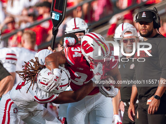 South Dakota defensive back Teven McKelvey #3 grabs the facemask of Wisconsin Badgers running back Jackson Acker #34 at Camp Randall Stadium...