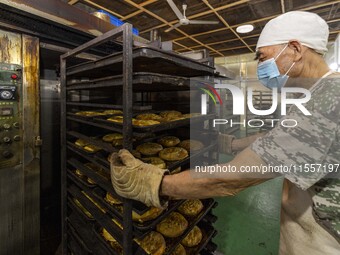 A worker takes a mooncake out of an electric oven at the production workshop of Dongfang Pastry Co., LTD., a time-honored pastry company in...