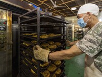 A worker takes a mooncake out of an electric oven at the production workshop of Dongfang Pastry Co., LTD., a time-honored pastry company in...