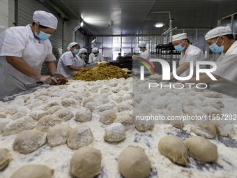 Workers make mooncakes at the production workshop of Dongfang Pastry Co., LTD., a time-honored pastry company in Taizhou, China, on Septembe...