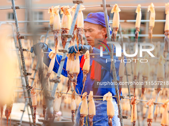 A worker dries squid at a seafood processing company in Zhoushan, China, on September 8, 2024. (