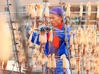 A worker dries squid at a seafood processing company in Zhoushan, China, on September 8, 2024. (