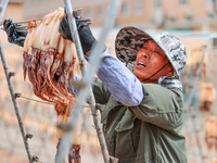 A worker dries squid at a seafood processing company in Zhoushan, China, on September 8, 2024. (