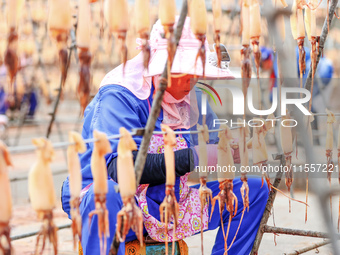 A worker dries squid at a seafood processing company in Zhoushan, China, on September 8, 2024. (