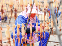 A worker dries squid at a seafood processing company in Zhoushan, China, on September 8, 2024. (