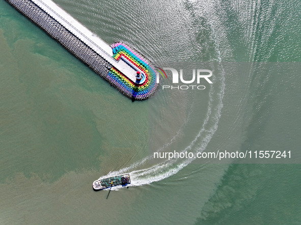 Coastal fishermen drive a fishing boat to transport oyster cage seedlings to a breeding area for spreading and stocking in Lianyungang, Chin...