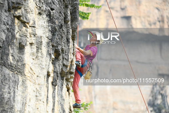 Contestants compete in the Red Dot competition at the Natural Rock Wall of Anlong National Mountain Outdoor Sports Demonstration Park in Qia...