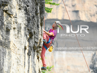 Contestants compete in the Red Dot competition at the Natural Rock Wall of Anlong National Mountain Outdoor Sports Demonstration Park in Qia...