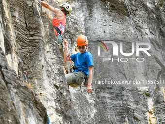 Contestants compete in the Red Dot competition at the Natural Rock Wall of Anlong National Mountain Outdoor Sports Demonstration Park in Qia...