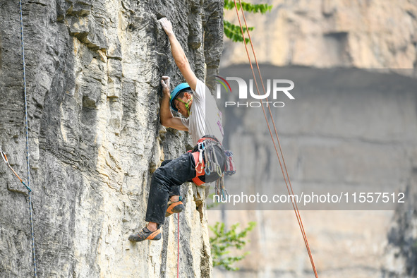 Contestants compete in the Red Dot competition at the Natural Rock Wall of Anlong National Mountain Outdoor Sports Demonstration Park in Qia...