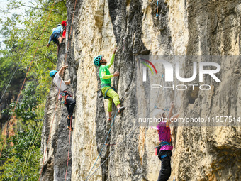 Contestants compete in the Red Dot competition at the Natural Rock Wall of Anlong National Mountain Outdoor Sports Demonstration Park in Qia...