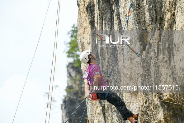 Contestants compete in the Red Dot competition at the Natural Rock Wall of Anlong National Mountain Outdoor Sports Demonstration Park in Qia...