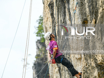 Contestants compete in the Red Dot competition at the Natural Rock Wall of Anlong National Mountain Outdoor Sports Demonstration Park in Qia...