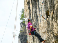 Contestants compete in the Red Dot competition at the Natural Rock Wall of Anlong National Mountain Outdoor Sports Demonstration Park in Qia...