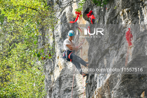 Contestants compete in the Red Dot competition at the Natural Rock Wall of Anlong National Mountain Outdoor Sports Demonstration Park in Qia...