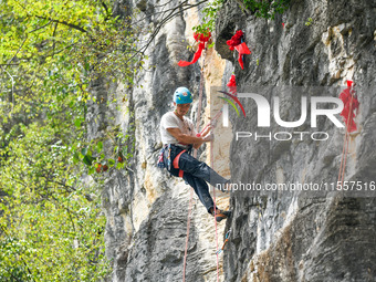 Contestants compete in the Red Dot competition at the Natural Rock Wall of Anlong National Mountain Outdoor Sports Demonstration Park in Qia...