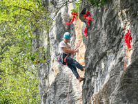 Contestants compete in the Red Dot competition at the Natural Rock Wall of Anlong National Mountain Outdoor Sports Demonstration Park in Qia...