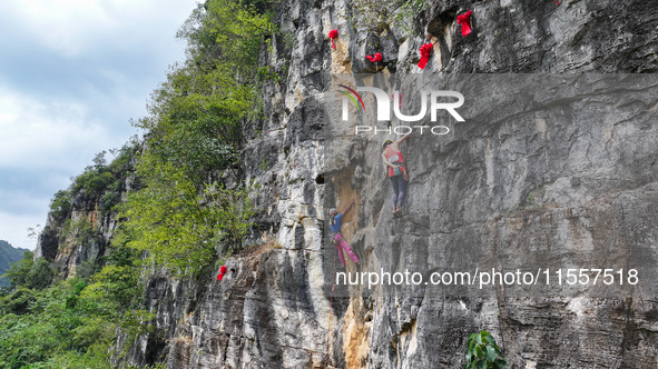 Contestants compete in the Red Dot competition at the Natural Rock Wall of Anlong National Mountain Outdoor Sports Demonstration Park in Qia...