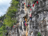 Contestants compete in the Red Dot competition at the Natural Rock Wall of Anlong National Mountain Outdoor Sports Demonstration Park in Qia...