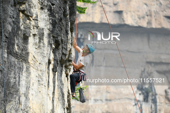 Contestants compete in the Red Dot competition at the Natural Rock Wall of Anlong National Mountain Outdoor Sports Demonstration Park in Qia...