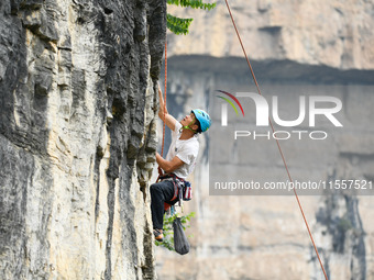 Contestants compete in the Red Dot competition at the Natural Rock Wall of Anlong National Mountain Outdoor Sports Demonstration Park in Qia...