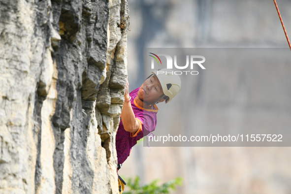 Contestants compete in the Red Dot competition at the Natural Rock Wall of Anlong National Mountain Outdoor Sports Demonstration Park in Qia...