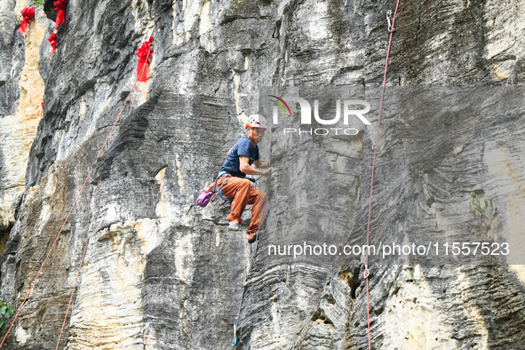 Contestants compete in the Red Dot competition at the Natural Rock Wall of Anlong National Mountain Outdoor Sports Demonstration Park in Qia...