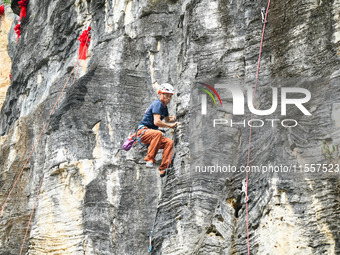 Contestants compete in the Red Dot competition at the Natural Rock Wall of Anlong National Mountain Outdoor Sports Demonstration Park in Qia...