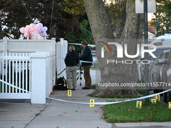 Crime scene investigators place evidence markers at the scene where three people are shot at 132-45 220th Street in Queens, New York, United...