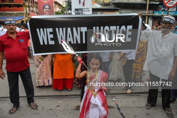 A little girl dressed as Devi Durga poses for the camera in front of a banner demanding ''We Want Justice'' during a protest rally in Kolkat...