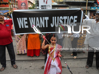 A little girl dressed as Devi Durga poses for the camera in front of a banner demanding ''We Want Justice'' during a protest rally in Kolkat...