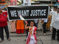 A little girl dressed as Devi Durga poses for the camera in front of a banner demanding ''We Want Justice'' during a protest rally in Kolkat...