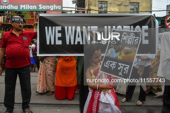 A little girl dressed as Devi Durga poses for the camera in front of a banner demanding ''We Want Justice'' during a protest rally in Kolkat...