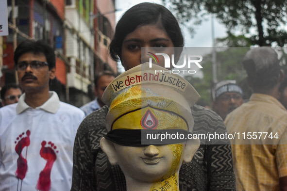 A lady carries the head of a Durga idol with various protest slogans written on it during a protest rally of artisans in Kolkata, India, on...