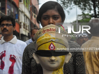 A lady carries the head of a Durga idol with various protest slogans written on it during a protest rally of artisans in Kolkata, India, on...