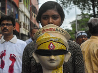 A lady carries the head of a Durga idol with various protest slogans written on it during a protest rally of artisans in Kolkata, India, on...