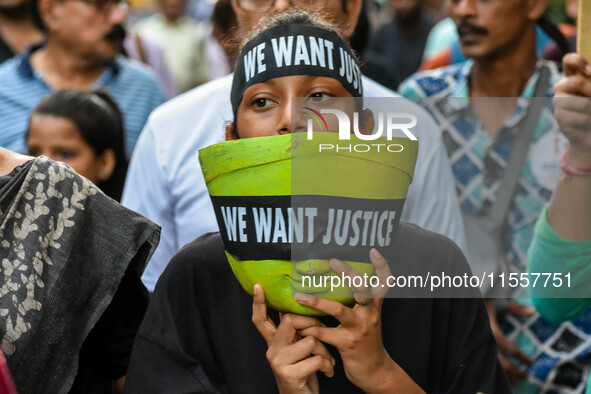 A girl carries the head of a Durga idol with a protest bandana wrapped around the eye during a protest rally in Kolkata, India, on September...