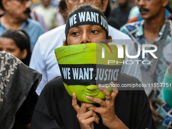 A girl carries the head of a Durga idol with a protest bandana wrapped around the eye during a protest rally in Kolkata, India, on September...