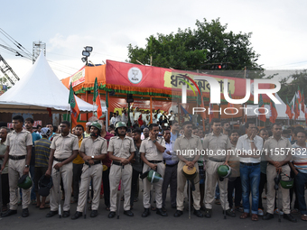 Police stand in front of the BJP agitation stage during a protest condemning the rape and murder of a trainee medic at a government-run hosp...