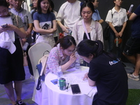 Job seekers learn about the demand for artificial intelligence digital technology positions at a job fair for science and technology talents...