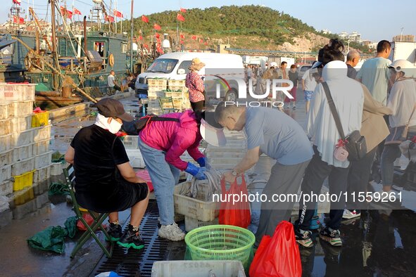 People buy seafood caught at Jimiya fishing port in Qingdao, Shandong province, China, on September 9, 2024. 