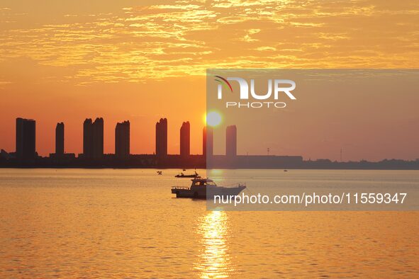 A fishing boat rides in Tangdao Bay illuminated by the rising sun in Qingdao, China, on September 9, 2024. 