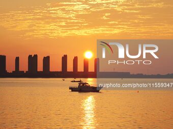 A fishing boat rides in Tangdao Bay illuminated by the rising sun in Qingdao, China, on September 9, 2024. (