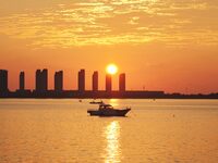 A fishing boat rides in Tangdao Bay illuminated by the rising sun in Qingdao, China, on September 9, 2024. (