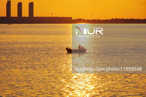 A fishing boat rides in Tangdao Bay illuminated by the rising sun in Qingdao, China, on September 9, 2024. 