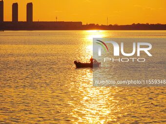 A fishing boat rides in Tangdao Bay illuminated by the rising sun in Qingdao, China, on September 9, 2024. (